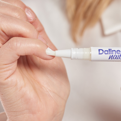 Close-up of a hand applying Daline Magic Pen nail cream with the brush applicator.