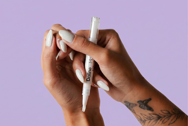 A close-up of a person's hands holding a white double-ended pen with the brand name 'Daline' printed on it, set against a solid light purple background. Magic pen. recover my nails. 